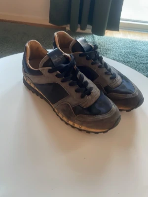 Valentino rockrunners  - Snygga Valentino Rockrunners sneakers i mörkblått och grått med camouflagemönster. Skorna har svarta snören, platt sula med nitar längs kanten och detaljer i mocka och syntet. Perfekt för dig som gillar exklusiva och unika sneakers. PRISET ÄR INTE HUGGET I STEN!🪨  Skriv vid minsta fundering 