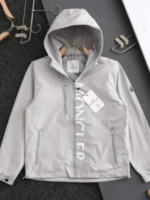 Moncler vindbreaker - Snygg grå vindjacka från Moncler med stor logga längs dragkedjan. Jackan har huva med snörning, tre framfickor med dragkedja och elastiska muddar vid ärmslut. Materialet är syntet och jackan har en clean look med Moncler-märke på ärmen.