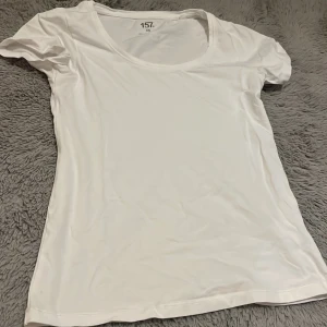 Vit kortärmad topp från 157 - En enkel och fräsch vit topp från 157 i storlek XS. Modellen är kortärmad med rund halsringning och har en slim passform. Perfekt att styla med jeans eller kjol för en clean look.