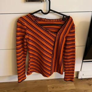 Randig orange stickad tröja - Snygg stickad tröja med orange och röda ränder, v-ringad och med långärmad design. 