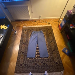 Baggy adidas byxor  - Väldigt baggy adidas byxor. Grå/silvrig färg. Dragkedja för fickorna.   Ytter Längd: 101 cm Inner längd: 70 cm Midja: 40 cm- 55 cm(stretch, kan dras åt också) Benöppning: 27 cm