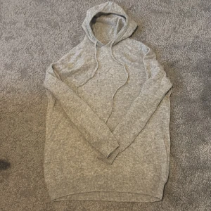 Stickad Hoddie av färgen grå - Tja, jag säljer den här snygga tröjan för otroligt bra pris. Tröjan är lite sönder vid luvan vilket ni kan se på sista bilden men syns knappast. Skriv om ni har några frågor.