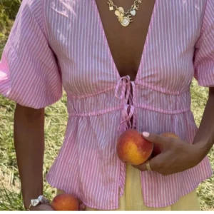 Rosa randig blus med snörning från Zara - Säljer en söt rosa blus från Zara med vita ränder, djup v-ringning och puffiga korta ärmar. Aldrig använd🥰