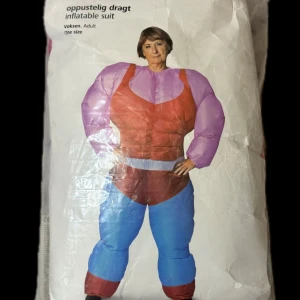 Uppblåsbar dräkt i rosa och blått - Säljer en uppblåsbar dräkt för vuxna i starka färger. Dräkten har rosa överdel, blå byxdel och vita detaljer i midjan. Tillverkad i syntetmaterial och kommer med fläkt och batteridosa för att blåsa upp dräkten. Perfekt för att sticka ut på maskerad eller temakväll. (Batterier ingår ej på köpet)