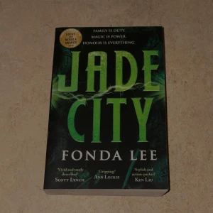 Jade City - En prisbelönt fantasybok där familj, magi och ära står i centrum. Perfekt för dig som gillar action, spänning och episka berättelser. Omslaget utstrålar mystik och kraft, och boken har hyllats av flera kända författare. En modern klassiker för unga vuxna!