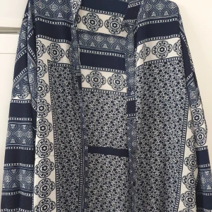 Klänning - Snygg klänning från Boohoo i blått och vitt med unikt mönster och långa ärmar. Klänningen har en avslappnad passform och är tillverkad i mjukt material. Perfekt för dig som gillar boho-vibbar och coola prints.