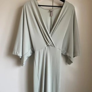 Ljusgrön långklänning  - Snygg ljusgrön långklänning från H&M med djup v-ringning och vida, korta ärmar. 