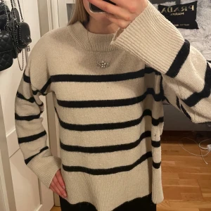 Gräddvit och svart randig stickad tröja - Stickad tröja i gräddvit/krämvit med svarta ränder. Passar XS-M, hur man vill att den ska sitta!