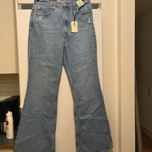 Levi's 70s High Flare ljusblå jeans - Ljusblå Levi's 70s High Flare jeans med hög midja och utsvängda ben. Klassisk femficksmodell i mjuk bomullsdenim med lätt slitna detaljer framtill. Snygg retrovibe och perfekt passform för dig som gillar flare och vintagekänsla.