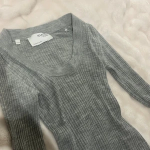 Grå ribbad klänning SELECTED FEMME - Grå ribbad klänning från SELECTED FEMME med lång ärm och u-ringad hals. Klänningen är figurnära och har en mjuk, stretchig känsla. Perfekt för dig som gillar en enkel men snygg look. Passar till sneakers eller boots.