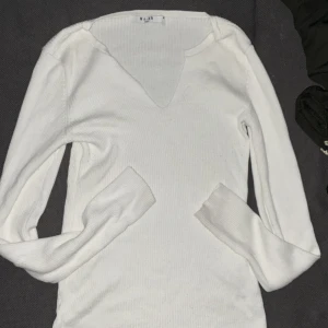 Vit ribbad långärmad tröja NAKD - Säljer en vit ribbad långärmad tröja från NA-KD med v-ringad hals. Tröjan är slim fit och har mjukt stickat material.storlek S, använt tröjan 2-3 gånger.