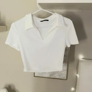 Vit croppad polotopp med krage - Snygg vit croppad polotopp från shein  med klassisk krage och v-ringad hals. Toppen har korta ärmar och är gjord i mjuk bomull som känns skön mot huden.🤍🌸