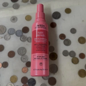 Aveda Nutriplenish Leave-in Conditioner - Säljer en rosa sprayflaska med Aveda Nutriplenish leave-in conditioner, 200 ml. Flaskan är gjord av plast och har en praktisk pump. Produkten är vegansk och passar alla hårtyper, ger näring och skydd till håret. Perfekt för dig som vill ha extra fukt och lättare utredning.