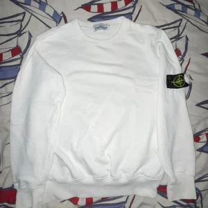 Vit Stone Island sweatshirt - Vit sweatshirt från Stone Island med klassisk rund hals och ikonisk logga på vänster ärm. Tröjan är i mjuk bomull och har ribbade muddar vid ärmslut och nederkant. Perfekt för en clean och stilren look. Priset kan diskuteras genom och dma 