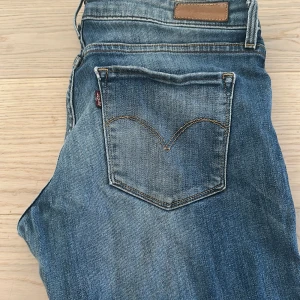 Levi's 511 skinny jeans blå - Snygga blå Levi's 511 jeans med skinny passform och klassisk femficksdesign. Jeansen har en mörk tvätt med slitningar och kontrastsömmar, samt den ikoniska Levi's-lappen på bakfickan. Perfekt för dig som gillar en smal siluett och tidlös stil. Dem är väldigt stretchiga. W29 L32