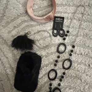 Montini örhängen och svart halsband - Säljer ett par svarta Montini örhängen i oval form samt ett matchande långt halsband med svarta pärlor och ovala detaljer. Perfekt för dig som gillar statement-smycken. Inkluderar även ett enkelt silverfärgat armband.