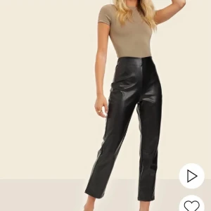 Svarta högmidjade skinnbyxor Bianca - Snygga svarta skinnbyxor från Bianca x Nelly med hög midja och raka ben. Byxorna har en stilren look med croppad längd och är tillverkade i ett glansigt syntetmaterial som ger en cool vibe. Perfekta för dig som vill sticka ut med en trendig stil.