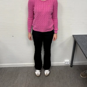 Rosa kabelstickad tröja från Morris lady - Rosa kabelstickad tröja från Morris lady med rund halsringning och diskret logga på bröstet. Tröjan har lång ärm och ribbade muddar vid ärmslut och nederkant. Perfekt för dig som gillar en klassisk men färgglad stil.