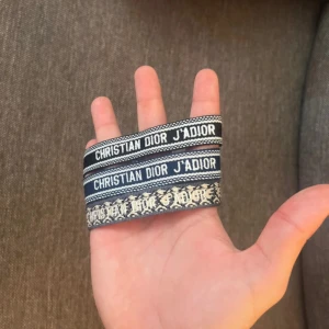 Christian Dior armband - Snygga Christian Dior J'Adior armband i tyg med broderad logga. Färgerna är marinblå, svart och grå ish med vita detaljer|                              Skriv vid funderingar                                            Priset kan självklart diskuteras
