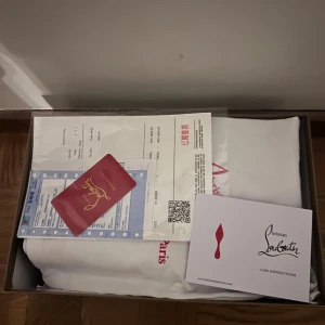 Svarta sneakers från Christian Louboutin - Säljer ett par svarta sneakers från Christian Louboutin med klassisk röd sula och diskret logga undertill. Skorna har rund tå, snörning och är tillverkade i mocka med mjukt beige foder. Perfekt för dig som gillar stilrena och lyxiga detaljer.