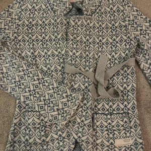 Mönstrad cardigan jacka Odd Molly - Säljer en snygg cardigan jacka från Odd Molly i stickad bomull med blått och vitt geometriskt mönster. Jackan har lång ärm, fickor framtill och ett matchande bälte i midjan. Perfekt för dig som gillar unika detaljer och skön stil.