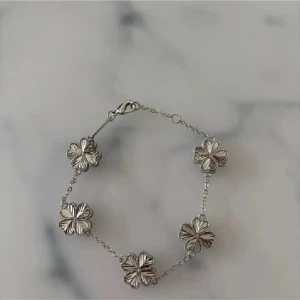 Silverfärgat armband med blommor - Snyggt armband i silverfärg med fem blommor som dekoration. Kedjan är tunn och har ett klassiskt lås. Perfekt för dig som gillar detaljer och vill ha något som sticker ut lite extra.
