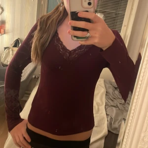 Vinröd långärmad topp med spets Gina Tricot - Säljer en vinröd långärmad topp från Gina Tricot med v-ringning och fina spetsdetaljer vid halsen. Använd 1 eller 2 gånger. 💕😌😇