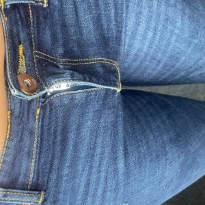 Mörkblå skinny jeans med slitningar - Säljer ett par mörkblå skinny jeans med snygga slitningar på knäna och klassiska gula sömmar. Jeansen har fem fickor, dragkedja och knapp framtill samt bälteshällor. Perfekta för dig som gillar en tight passform och lite edge i looken. Storlek 160 men passar mig som bär 32 så passar S/M🤗aldrig använda men lapp avtagen 