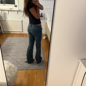 Blå bootcut jeans låg midja - Säljer ett par blå jeans med bootcut och låg midja. Jeansen har klassiska fickor fram och bak, samt markerade sömmar längs benen. Materialet är jeans och passformen är normal med lite utsvängda ben. Perfekt för dig som gillar retrovibbar och avslappnad stil. Priset kan diskuteras men dem är köpa för 700💗💗