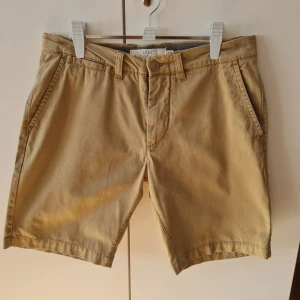Beige chinosshorts från H&M strl W29 - Snygga beige chinosshorts från H&M med klassisk design. De har en knapp och dragkedja framtill samt två sidofickor och två bakfickor med knappar. Storlek EUR 29. Kan hämtas i Vallentuna.