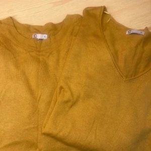 Två Gula tröjor från Cubus - Mysiga gula  tröjor från Cubus i storlek S. Tröjan har v-ringad hals och långa ärmar med ribbade muddar. Perfekt för lager-på-lager och ger en snygg färgklick till din outfit.