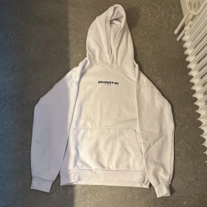 Vit hoodie Chaotic med anime-tryck - Säljer en vit hoodie från Chaotic med svart text på bröstet och stort anime-inspirerat tryck på ryggen. Hoodien har huva, känguruficka och långa ärmar. Perfekt för dig som gillar streetwear och anime vibes. Hoddien har några fläckar men det är ingenting man märker när man har på sig den.