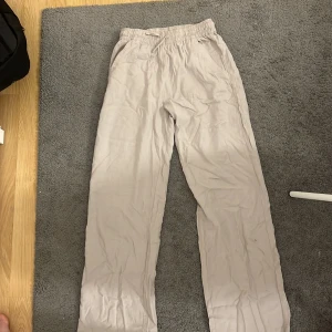 Beiga linnebyxor med resårmidja - Säljer ett par beiga linnebyxor med resår och snörning i midjan. Byxorna har raka ben och sidfickor, perfekta för en chill och avslappnad stil. Lätta och luftiga, passar grymt bra till sommaren.