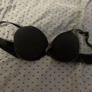 Svart BH från H&M 70B - Svart BH från H&M i storlek 70B. Den har vadderade kupor och justerbara axelband för perfekt passform. Enkel och stilren design som funkar till allt. Materialet är mjukt och bekvämt mot huden.