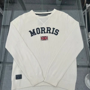Vit stickad Morris-tröja XL – preppy & klassisk - Snygg vit stickad tröja från Morris i storlek XL. Broderad logga och flagga framtill, preppy och tidlös stil i mjuk bomull. I mycket bra skick, perfekt till både jeans och chinos! 
