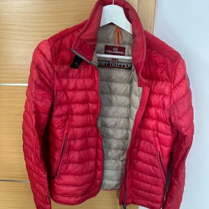 Röd pufferjacka från Parajumpers S - Säljer en rosa pufferjacka från Parajumpers i storlek S. Jackan har quiltad design, dragkedja framtill och två sidofickor med dragkedja. Klassisk Parajumpers-logga på ärmen och beige insida. Perfekt för dig som vill ha en lätt och snygg jacka.