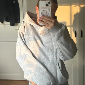 Ljusgrå hoodie med huva - En stilren ljusgrå hoodie med huva och långa ärmar. Tröjan har en klassisk passform och är tillverkad i mjukt bomullsmaterial. Perfekt för chill dagar eller när du vill ha en enkel och clean look.