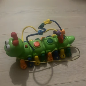 Elektronisk aktivitetslarv - Färgglad elektronisk larv med knappar, ljud och ljus. Perfekt för små barn, stimulerar motorik och lärande. Flera interaktiva funktioner och robust plastkonstruktion. Inga synliga defekter eller slitage varan är i gott skick.