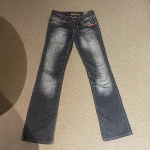 Super snygga lowwaist bootcut jeans från Crazy Miss - Snygga blå jeans från Crazy Miss, bootcut och lågmidjade. Materialet är jeans med en tvättad look och coola detaljer på bakfickorna. Super bra passform, bra i längd för folk från 160-175. Köpta för 600kr.😍💕 Storlek 34 men passar mig med 36 bra också.