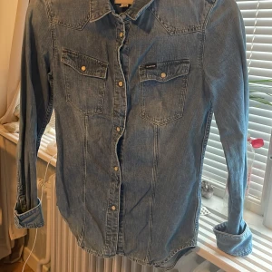 Jeansskjorta från G-Star RAW XS - Snygg blå jeansskjorta från G-Star RAW i klassisk modell med tryckknappar och två bröstfickor. Skjortan har lång ärm och cool westernkänsla, perfekt att styla med dina favoritjeans eller kjol.