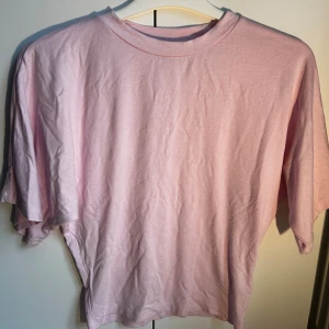 Ljusrosa t-shirt som sitter tight vid botten och löst vid toppen - Fin ljusrosa t-shirt som sitter tight där nere men löst där uppe på tröjan från lager 157 i storlek XS. Den är aldrig använd🥰 skriv gärna ifall ni vill se fler bilder av tröjan!