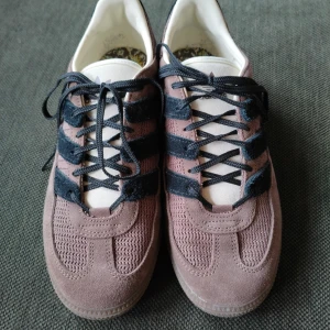 Adidas sneakers  - Säljer ett par Adidas sneakers i brun mocka, svarta ränder och svarta snören. Extra skosnören i matchande färg medföljer. Endast använda ca 5 gånger och är i mycket fint skick!