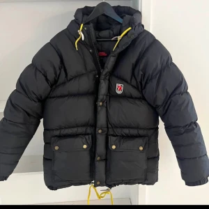 Svart pufferjacka från Fjällräven - Fjällräven expedition xxxs svart (jag brukar ha small i kläder och den sitter toppen!)  Fin jacka från Fjällräven och framförallt, världens varmaste!   Fint skick, fina läderflärpar. Dock ett litet hål i ena ärmen. Se bild. (Inget jag sett förens nu när jag fotade jackan, så väldigt litet :))  
