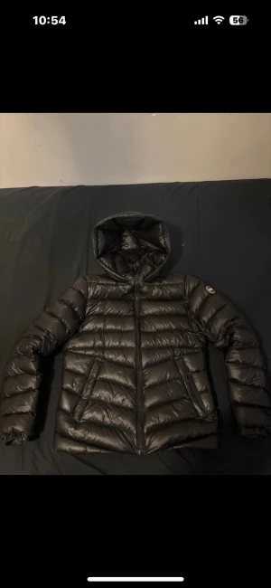 COLMAR vinterjacka svart - Säljer en svart vinter från Colmar med huva och snyggt quiltad design. Jackan har dragkedja framtill, två sidofickor och Colmar-logga på ärmen. Materialet är glansigt och jackan är lätt men ändå varm, perfekt för kalla dagar.