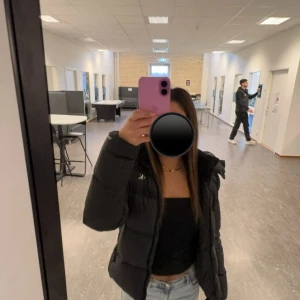 Svart pufferjacka från Calvin Klein - Säljer en svart pufferjacka från Calvin Klein med hög krage och diskret CK-logga på bröstet. Jackan har en snygg, quiltad design och dragkedja framtill. Perfekt för dig som vill ha en stilren och varm jacka med modern passform.