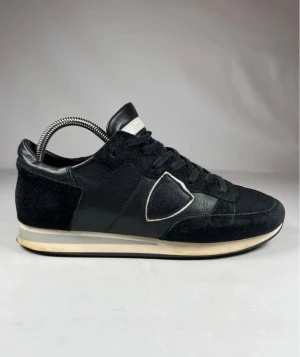  Philippe Model TRPX - Snygga svarta sneakers från Philippe Model med klassisk design. Skorna har ovandel i skinn och mocka, meshpartier och vita detaljer runt loggan. Platt sula i vitt och svart, samt snörning framtill. Perfekta för dig som gillar stilrena och exklusiva sneakers. Pris kan alltid diskuteras. Skriv om frågor uppstår. 