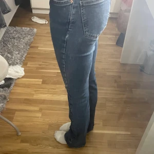 Blå bootcut jeans från Perfect Jeans - Snygga blå jeans från Gina trico i storlek 32 med klassisk bootcut-passform. Jeansen har hög midja, fem fickor och dragkedja med knapp framtill. Materialet är slitstarkt denim med kontrastsömmar och en mörk tvätt som ger en cool vibe.