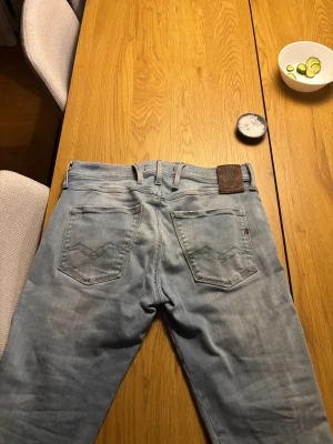 Replay anbass - Säljer ett par ljusblå jeans från Replay med klassisk femficksdesign och snygga slitningar. Jeansen har tapered passform, normal midja och är tillverkade i mjukt jeansmaterial. Läderpatch med Replay-logga bak i midjan och diskreta detaljer på fickorna. Bara skriva vid frågor!