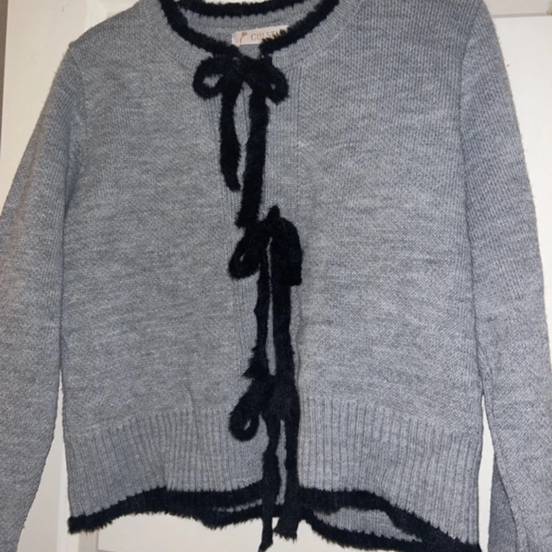 Grå kofta med svarta rosetter