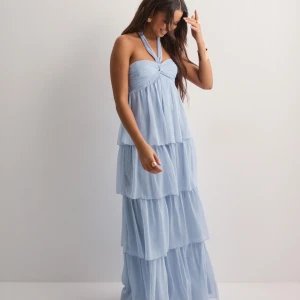 Ljusblå långklänning med volanger - Säljer en ljusblå långklänning med halterneck och flera lager volanger. Hade på nians bal, endast använd en gång💕 